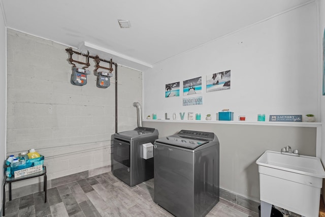 washroom featuring wood-type flooring, separate washer and dryer, and sink