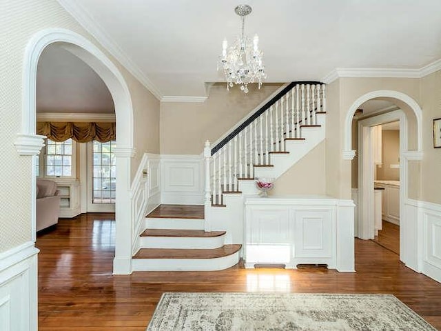 stairway featuring hardwood / wood-style flooring, crown molding, and an inviting chandelier