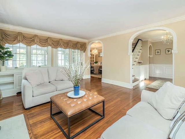 living room with crown molding, wood-type flooring, and a chandelier