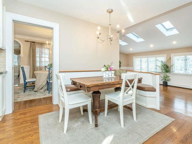 dining room featuring an inviting chandelier, vaulted ceiling, and light hardwood / wood-style floors