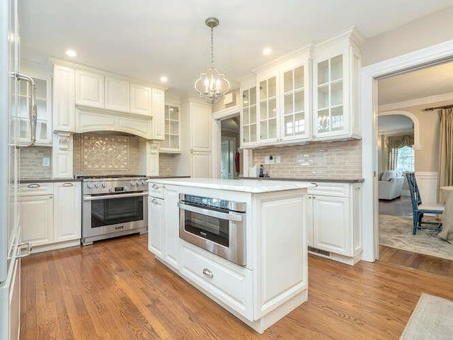 kitchen featuring pendant lighting, stainless steel appliances, wood-type flooring, and white cabinets