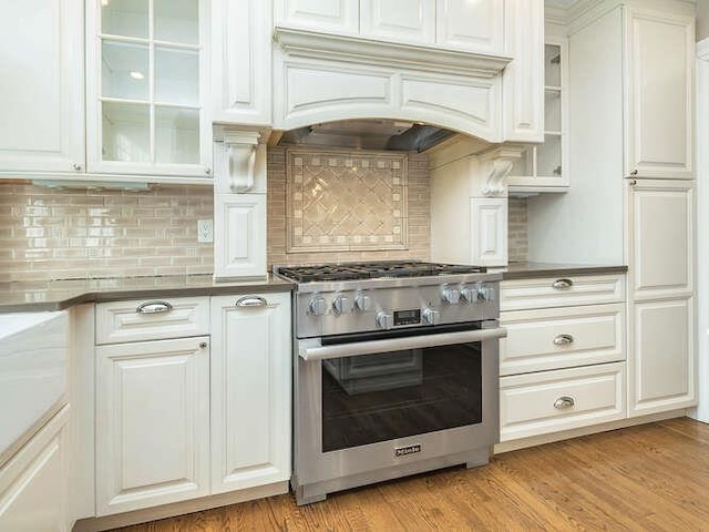 kitchen with premium range hood, white cabinetry, light hardwood / wood-style floors, and stainless steel stove