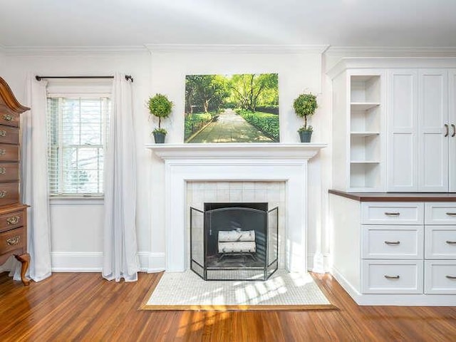 unfurnished living room with crown molding, wood-type flooring, and a fireplace