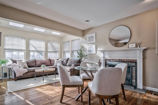 dining area with a brick fireplace, a wealth of natural light, and hardwood / wood-style floors