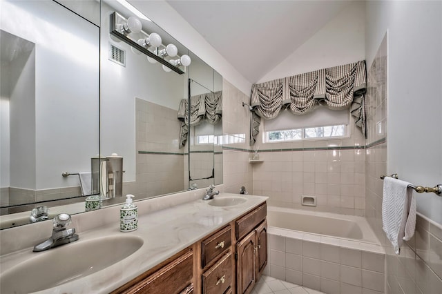 bathroom with tile patterned floors, lofted ceiling, vanity, and tiled tub