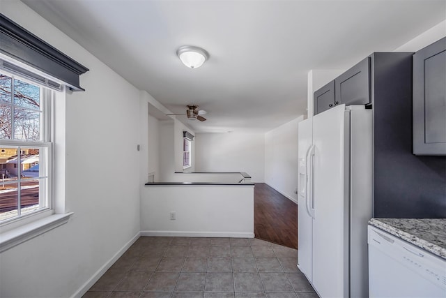 kitchen with gray cabinetry, light tile patterned floors, ceiling fan, light stone countertops, and white appliances