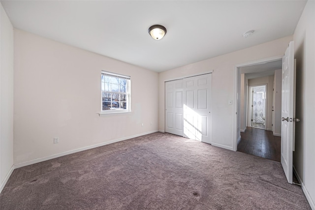 unfurnished bedroom with dark colored carpet and a closet