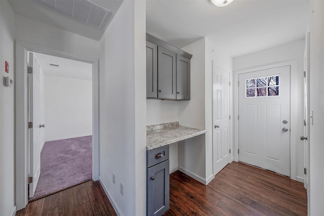 interior space with light stone counters, dark hardwood / wood-style flooring, gray cabinets, and built in desk