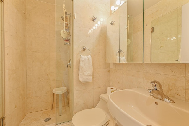 bathroom featuring tile walls, sink, a shower with door, and toilet