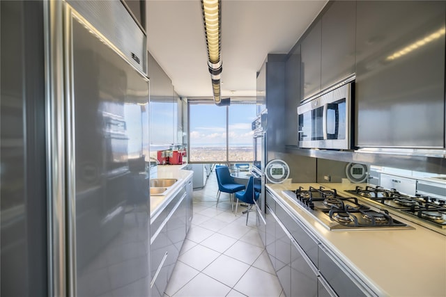 kitchen featuring light tile patterned flooring, a wall of windows, stainless steel appliances, and sink