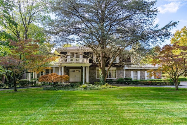 view of front facade with a front yard and a balcony