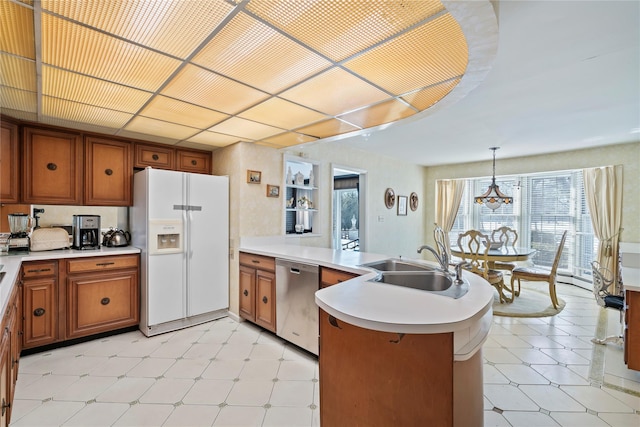 kitchen featuring sink, hanging light fixtures, white refrigerator with ice dispenser, stainless steel dishwasher, and kitchen peninsula