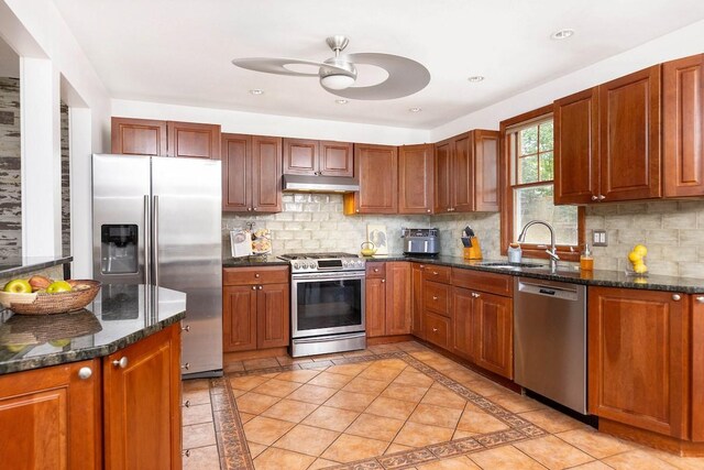 kitchen featuring appliances with stainless steel finishes, sink, dark stone counters, and tasteful backsplash