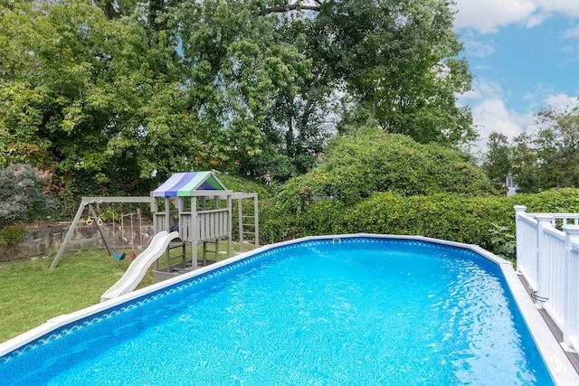 view of swimming pool with a playground, a water slide, and a yard