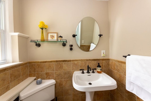 bathroom with toilet, sink, and tile walls