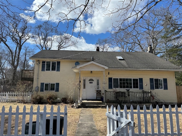 view of front of home with a fenced front yard, a chimney, and a shingled roof