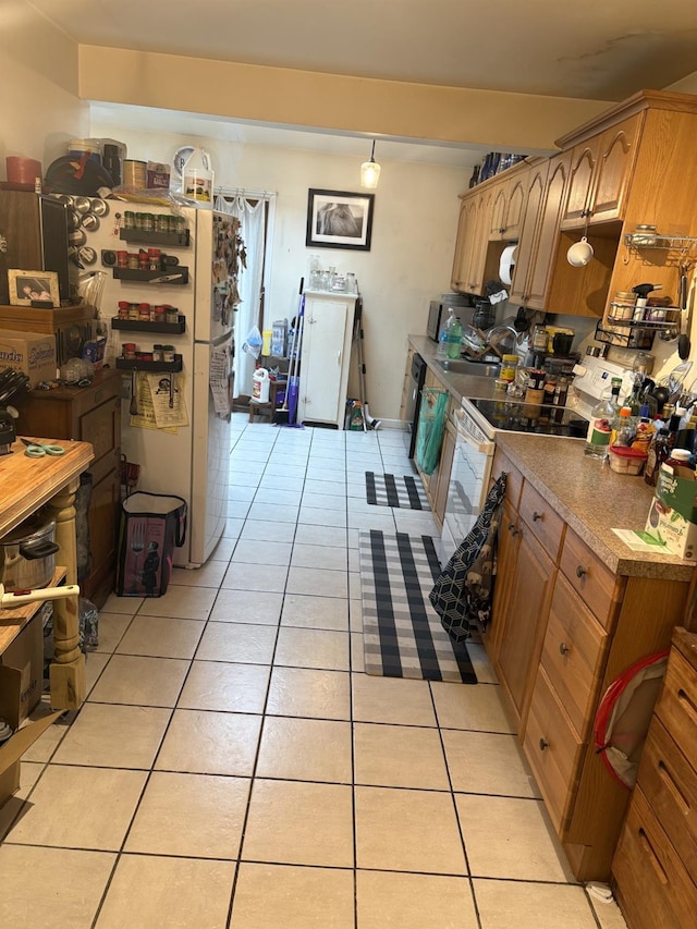 kitchen with light countertops, light tile patterned floors, freestanding refrigerator, electric range, and a sink