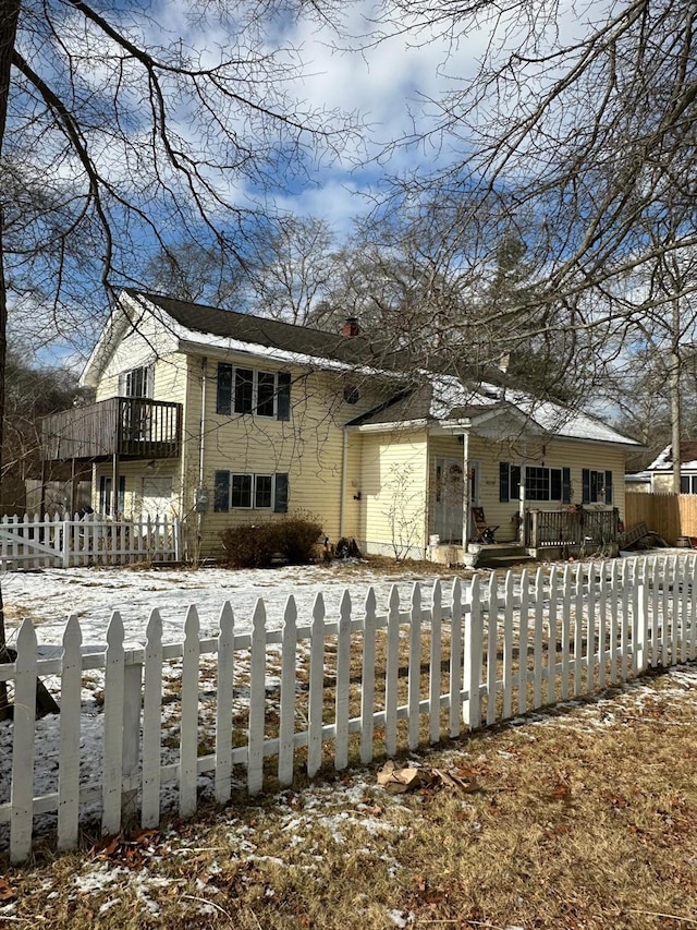 view of front of house featuring a fenced front yard, a balcony, and a chimney