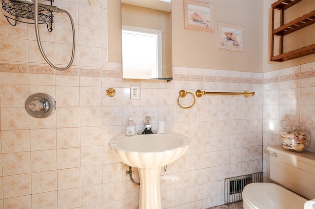 bathroom with a shower, tile walls, and toilet