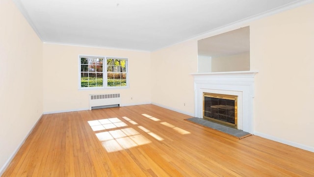 unfurnished living room featuring ornamental molding, radiator, and light hardwood / wood-style floors