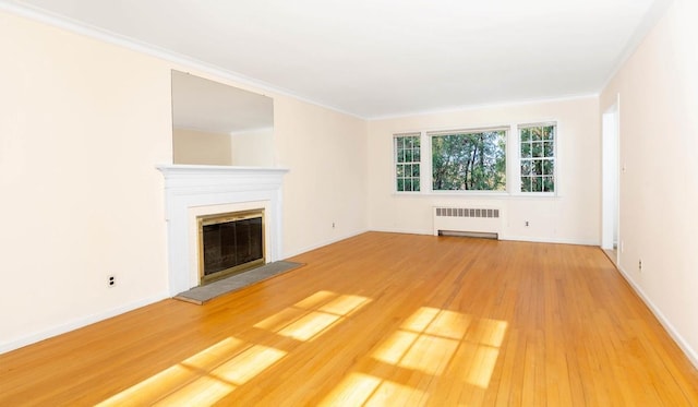 unfurnished living room featuring hardwood / wood-style floors, ornamental molding, and radiator heating unit