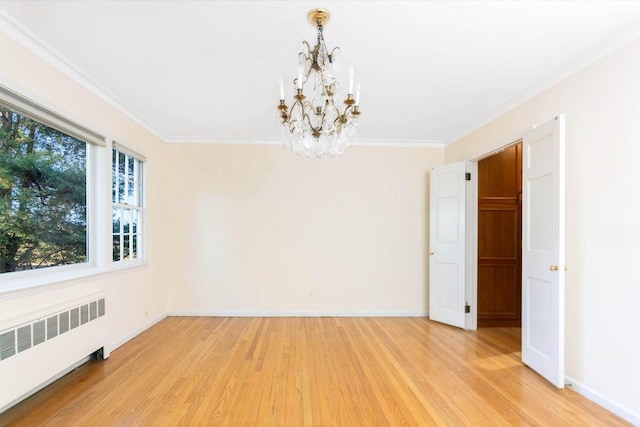 empty room with ornamental molding, radiator heating unit, a chandelier, and light wood-type flooring