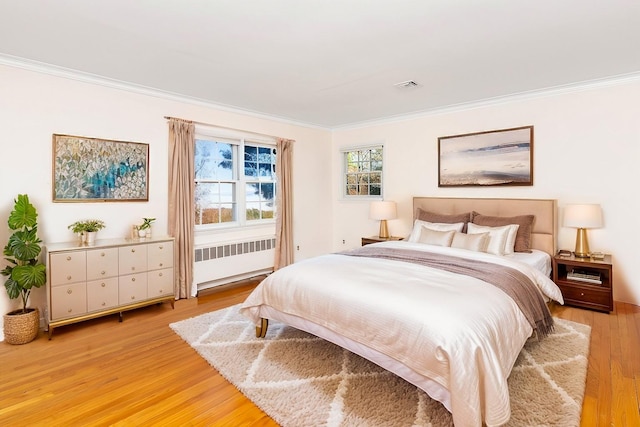 bedroom with ornamental molding, radiator, and light hardwood / wood-style flooring