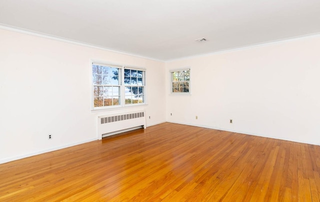 empty room with ornamental molding, radiator, and wood-type flooring