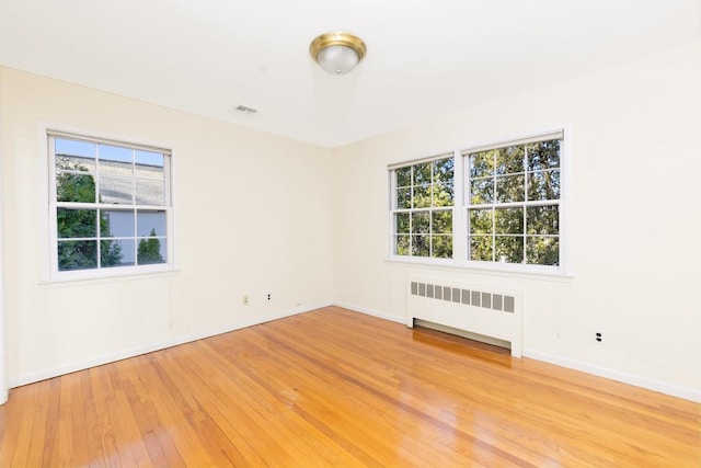 spare room featuring radiator and light hardwood / wood-style floors