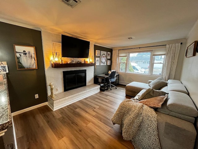 living room with crown molding, a brick fireplace, hardwood / wood-style flooring, and a baseboard radiator