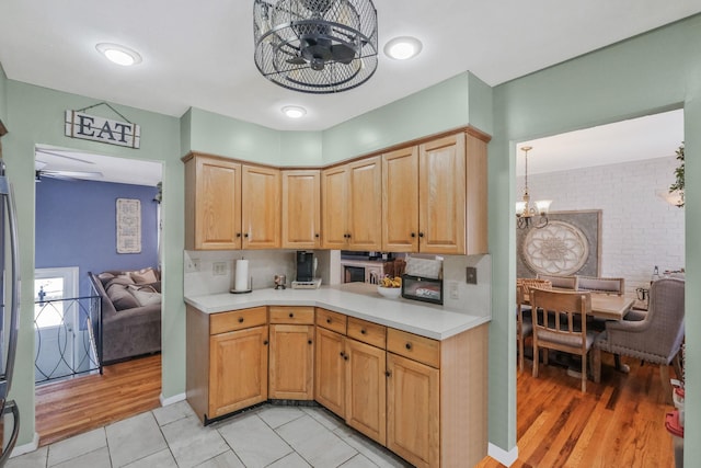 kitchen with light tile patterned flooring, light brown cabinetry, and ceiling fan with notable chandelier