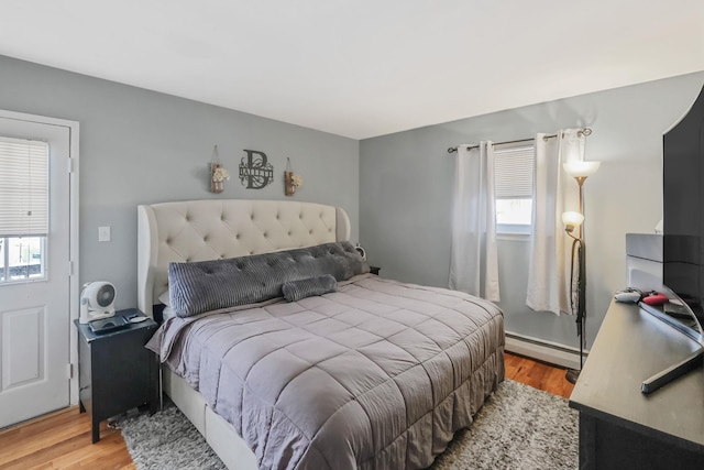 bedroom with a baseboard heating unit and light hardwood / wood-style flooring