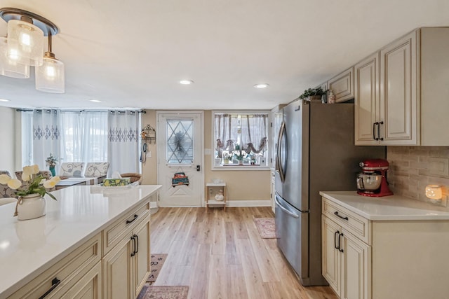 kitchen featuring cream cabinets, pendant lighting, light hardwood / wood-style floors, and decorative backsplash