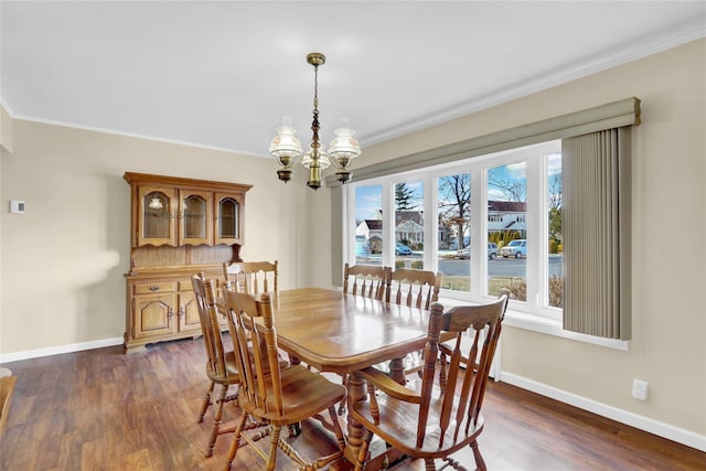 dining room featuring dark hardwood / wood-style flooring, ornamental molding, and an inviting chandelier