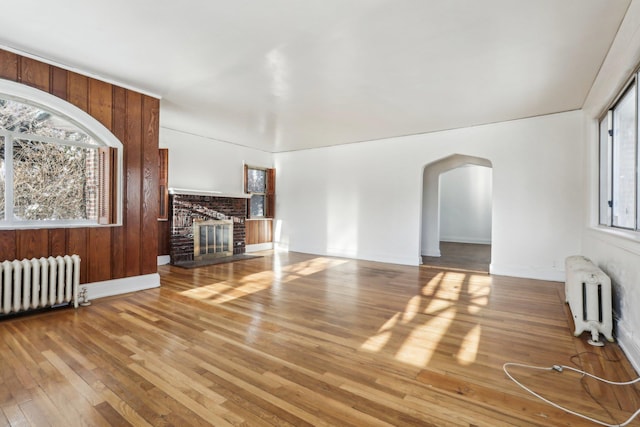 unfurnished living room with hardwood / wood-style flooring, a fireplace, and radiator