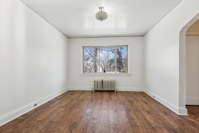 spare room featuring dark hardwood / wood-style flooring and radiator