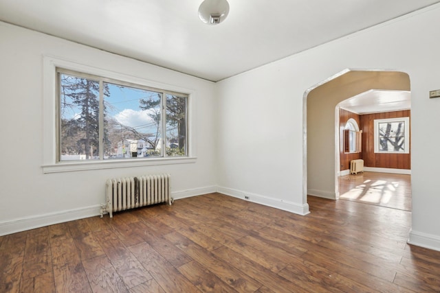 empty room with dark hardwood / wood-style flooring and radiator