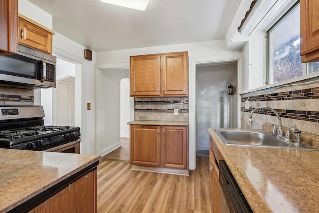 kitchen featuring appliances with stainless steel finishes, light hardwood / wood-style floors, sink, and decorative backsplash