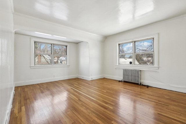 empty room with radiator heating unit and hardwood / wood-style floors