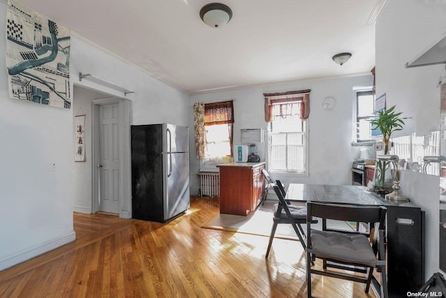 dining room featuring ornamental molding, radiator, and light hardwood / wood-style flooring