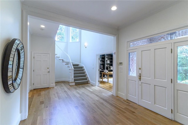 foyer entrance with ornamental molding and light wood-type flooring