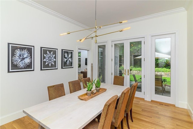 dining room featuring an inviting chandelier, ornamental molding, light hardwood / wood-style floors, and french doors