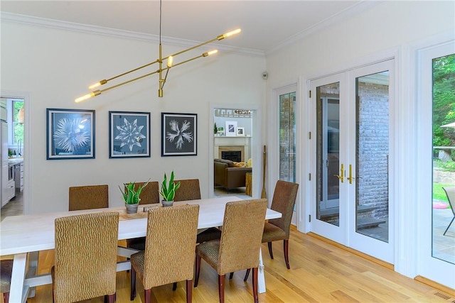 dining room with light hardwood / wood-style floors, ornamental molding, and french doors