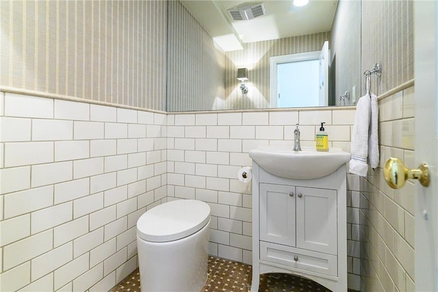 bathroom featuring vanity, tile walls, and toilet