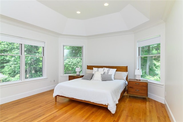 bedroom with crown molding, a tray ceiling, and light hardwood / wood-style flooring