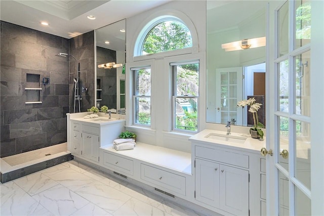 bathroom with a tile shower, vanity, and ornamental molding