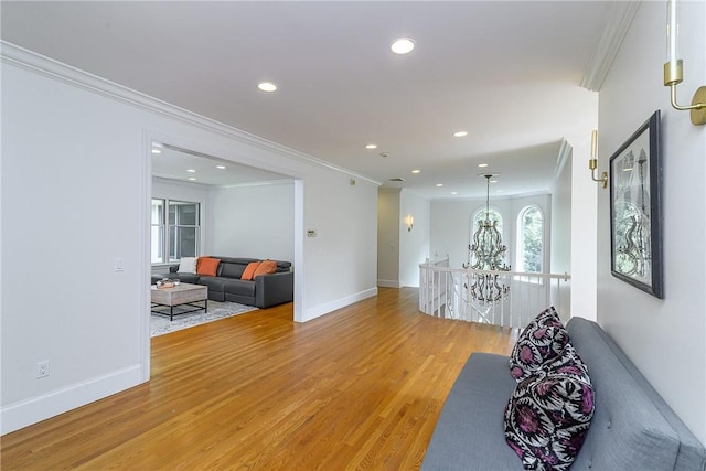 living room featuring wood-type flooring, ornamental molding, and a chandelier