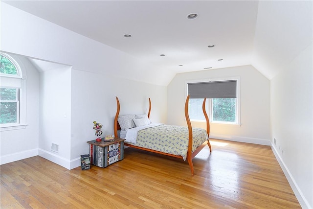 bedroom with multiple windows, hardwood / wood-style floors, and lofted ceiling