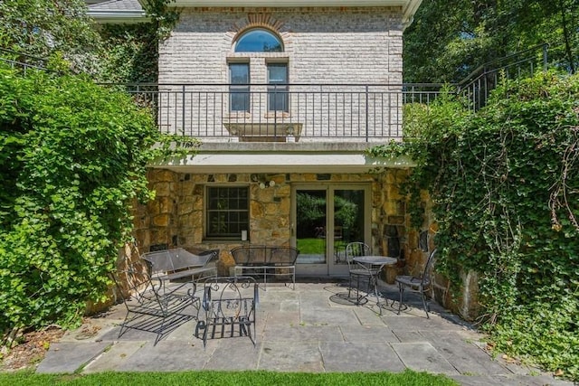 back of property with french doors, a balcony, and a patio area