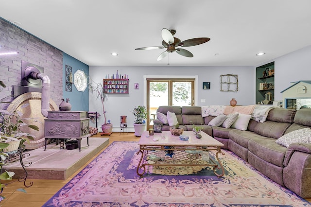 living room featuring recessed lighting, baseboard heating, a ceiling fan, a wood stove, and wood finished floors